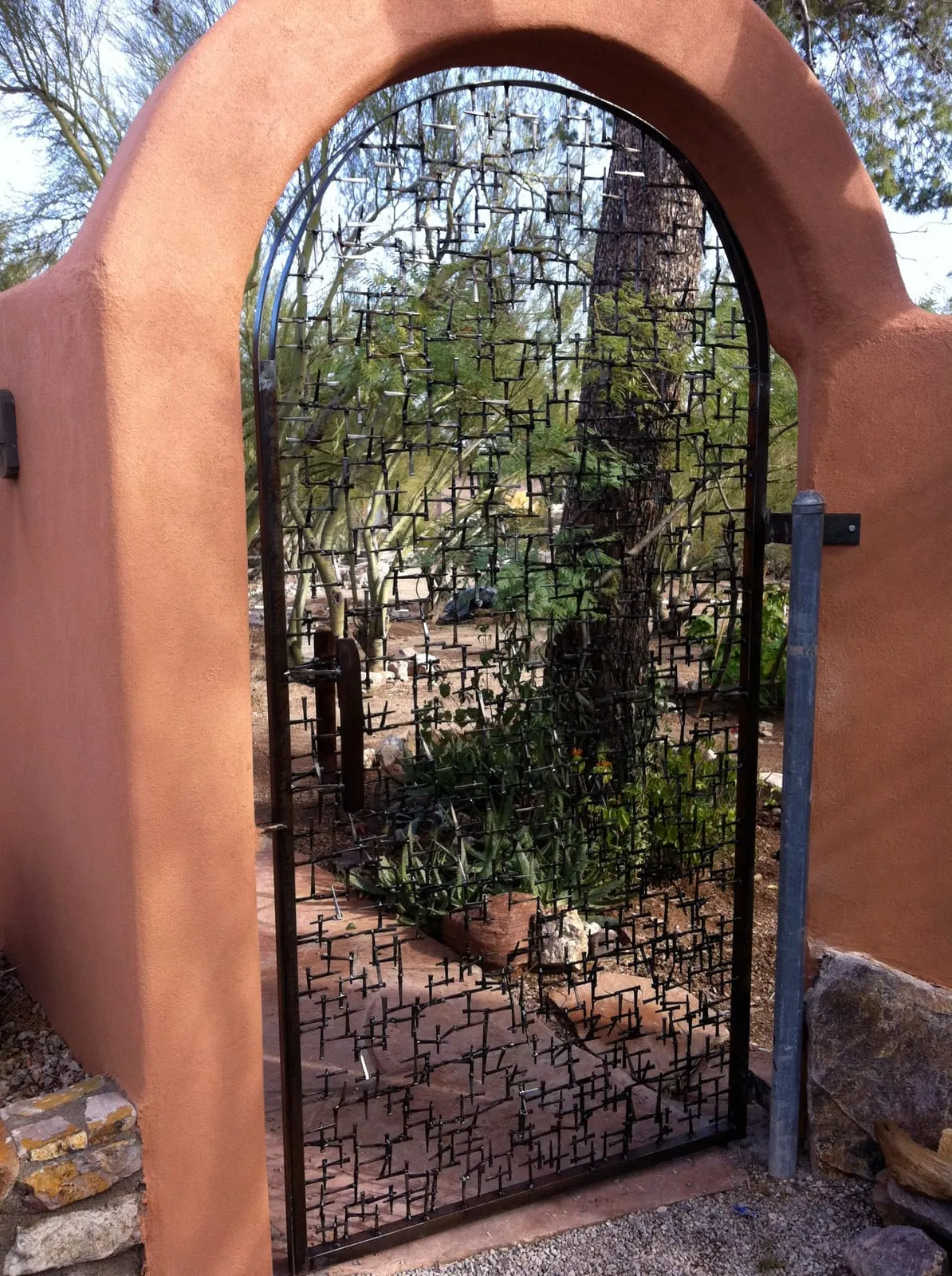 A garden gate John built from nails, set into an adobe wall